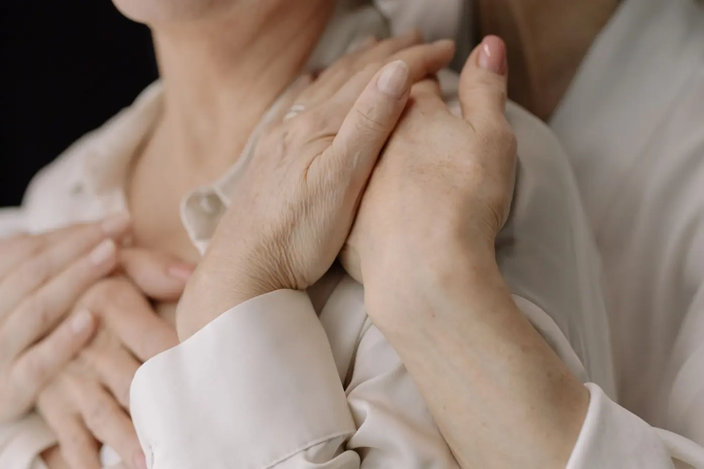 A carer's hands gently supporting another person's hands